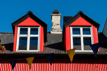 Red building with dormer windows and festive bunting against a clear blue sky.