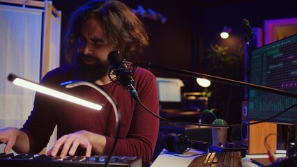 Skilled musician composing a song on piano midi controller, working with mixing console and daw...