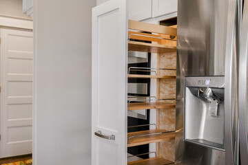 Modern Kitchen With Pull-Out Pantry Shelves And Stainless Steel Fridge