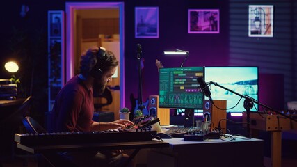 Joyful artist playing piano keyboard and recording tunes for mixing and mastering session, enjoying midi controller performance in home studio. Energetic music producer creating soundtracks. Camera A.