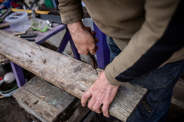 Person Using Pliers to Remove Nails From Old Wood Plank