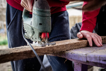 Person Cutting Wood With Electric Jigsaw Outdoors