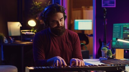 Young artist composing a song on electronic piano keyboard at home recording studio. Audio engineer...