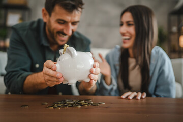 Adult couple save money coins in the piggy bank at home