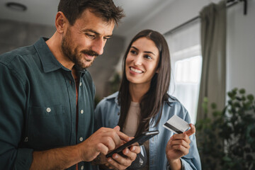 Portrait of couple buy online on mobile phone with credit card at home