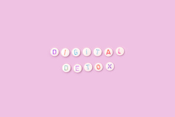 Digital detox. Quote made of white round beads with colorful letters on a purple background.