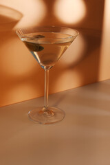 Glass of martini with olives on color background