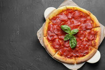 Tasty pepperoni pizza on black textured table, top view. Space for text