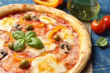 Delicious vegetarian pizza and ingredients on blue wooden table, closeup