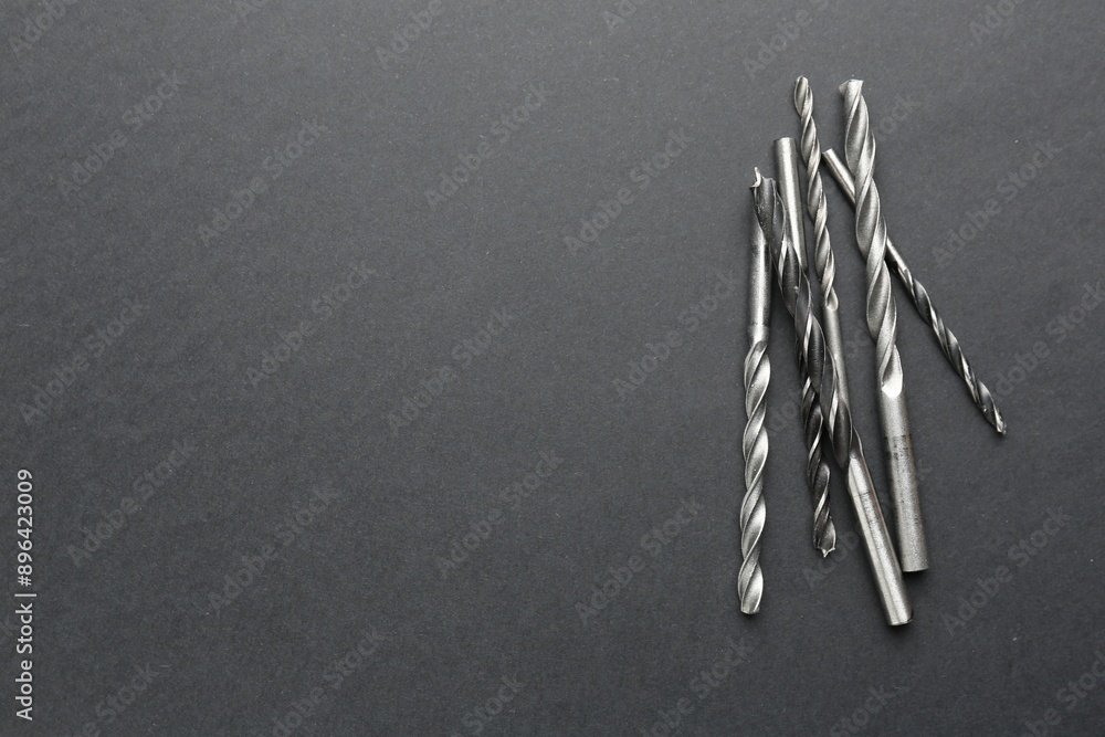 Poster many different drill bits on grey table, top view. space for text