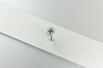 Metal screw in white panel on light table, above view