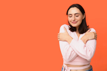Obraz premium Young woman hugging herself on orange background