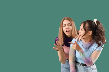 Young women gossiping on green background