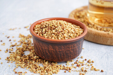 Bowl with raw buckwheat grains on light background, closeup