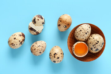 Wooden bowl with fresh quail eggs on blue background