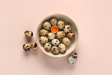Bowl with fresh quail eggs on beige background