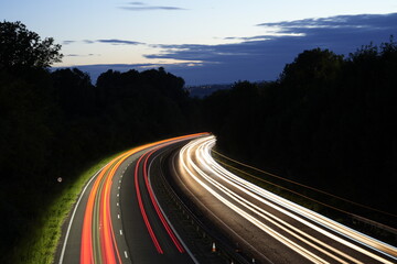 Traffic at night long exposure. Car lights in motorway. Viehicle trail lights in darkness. Front and rear lights in darkness.Highway light trail. England motorway night passing traffic. Dark backdrop