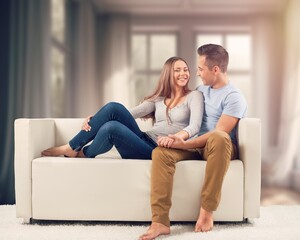 Happy romantic couple sitting on couch at room