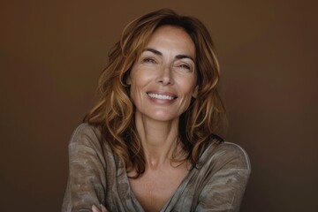 Fototapeta premium Ageing woman with well maintained skin white teeth and a positive expression gazes happily above with arms crossed highlighting beauty and age