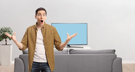 Surprised young man in front of a tv