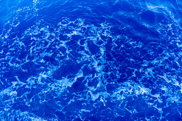 Texture of blue water under sun beams.