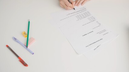 Female draws correct answer in math exam test paper with pencil. Student filling up the answer sheet, writing right answer, top view shot.