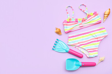 Set of beach accessories for children, swimsuit and seashells on lilac background