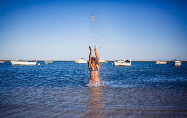 woman on the beach trowing water to the sky