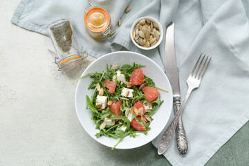 Bowl with healthy vegetable salad, napkin, spices and cutlery on grey grunge background