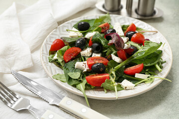 Plate with healthy vegetable salad, napkin and cutlery on grey grunge background