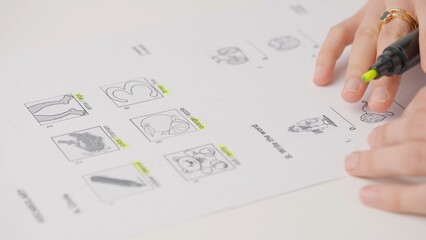 Female highlighting correct answers in exam test paper with yellow marker. Student filling up the answer sheet, choosing right answer, close up shot.
