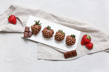 Plate with chocolate covered strawberries on grey background