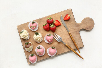 Wooden board with chocolate covered strawberries and fresh berries on white background