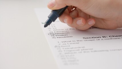 Obraz premium Professional school or college teacher grades a homework exam papers of students. Woman draws check marks with green marker for right answers in test.