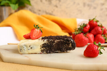 Board with tasty cheesecake pop and strawberry on table