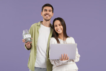 Young couple with laptop and jar of money for car on lilac background