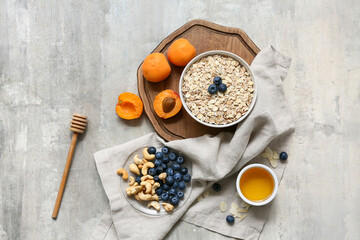 Napkin, wooden tray, apricot, bowl with raw oatmeal and berries on grunge background