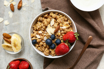 Napkin, bowl with tasty granola, nuts and berries on grunge background, closeup