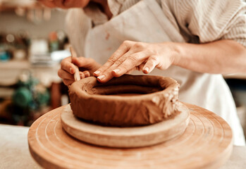 Hands, clay and pottery wheel in studio with tools, craft and skills for product at small business....