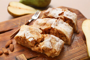 Wooden board with pieces of tasty pear strudel, closeup