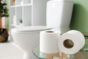Paper rolls on table near toilet bowl in restroom