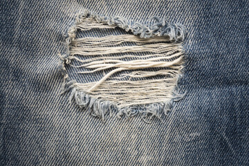 Ripped denim on blue jeans. Denim jeans fashion background. Blue jean fabric texture background....
