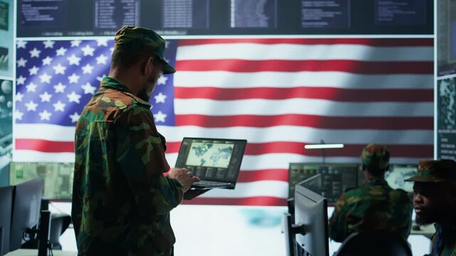 US soldiers operating in a high tech cybersecurity command post, managing state secrets and classified information. Protecting servers against digital threats and cyber warfare. Camera B.
