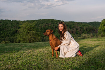 young beautiful female playing with her dog outside in the backyard with a gorgeous hill view