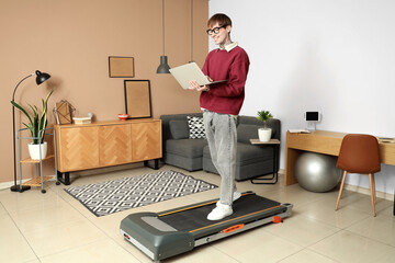 Young businessman working with laptop on treadmill in office