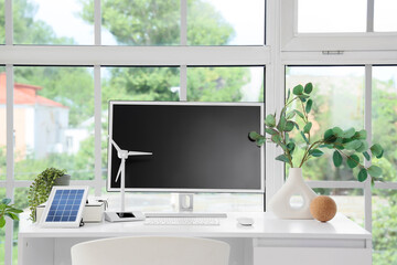 Engineer's workplace with computer monitor and wind turbine model in office
