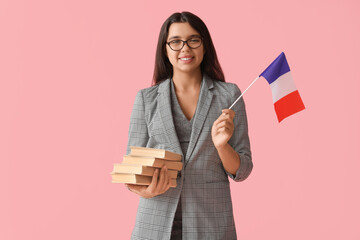 Female French language teacher with books and flag on pink background