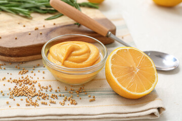 Bowl with creamy mustard, spoon and lemon on white background