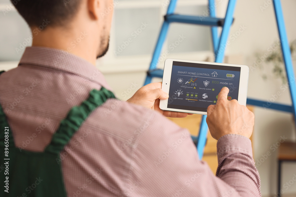 Poster male worker using tablet computer with installed alarm system in room, closeup