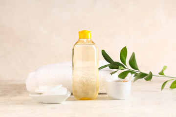 Bottle of micellar water, green twig, bowls with cotton pads and buds on grunge background